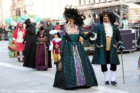 Couple in green and gold 18th-century costumes parading in St Mark's Square, Venice