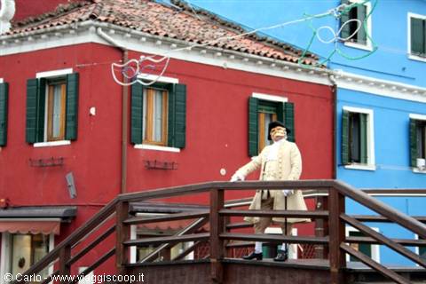 Historical costume on a wooden bridge in front of Burano's colored houses