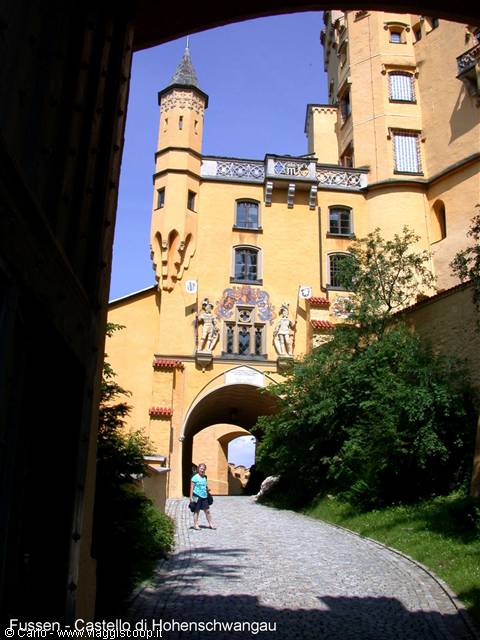 Tourist under Hohenschwangau's archway, yellow facade and sunlit tower