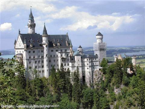 Neuschwanstein castle in light stone among green firs, towers and cloudy sky
