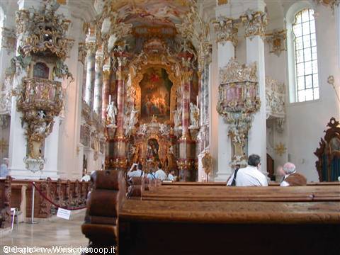 Baroque interior of the Wieskirche: gilded altar, carved pulpit, visitors among wooden pews