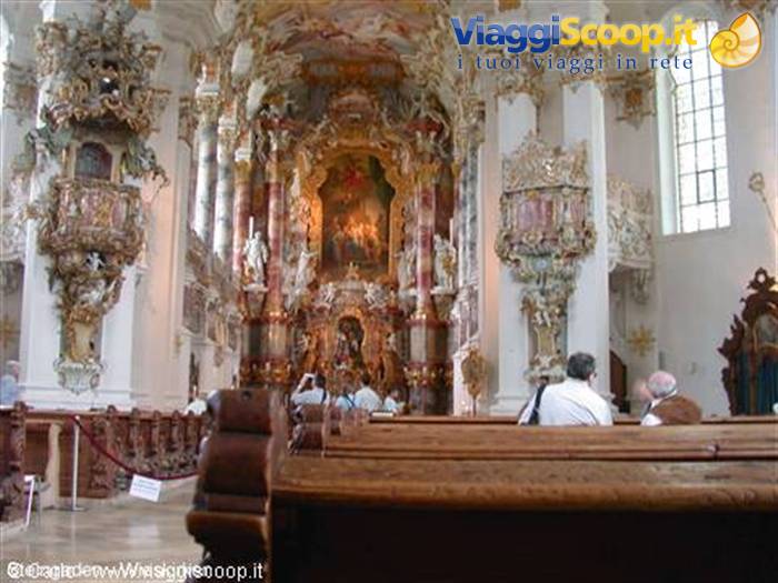 Baroque interior of the Wieskirche: gilded altar, carved pulpit, visitors among wooden pews