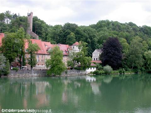 Green river with red-roofed houses and medieval tower among trees