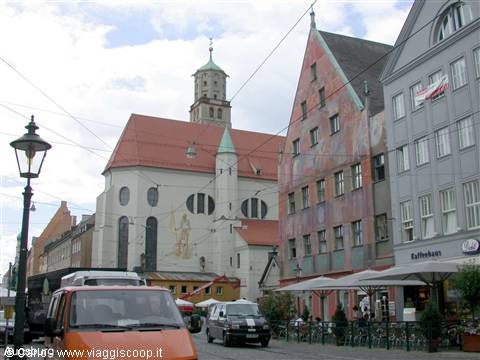 White church with green tower beside colorful houses in Munich