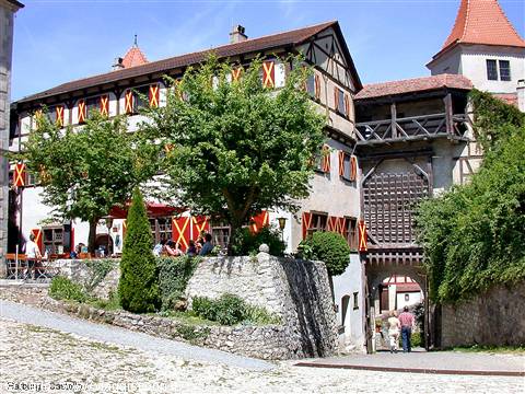 Harburg Castle: half-timbered building with red shutters, wooden gate, visitors under trees
