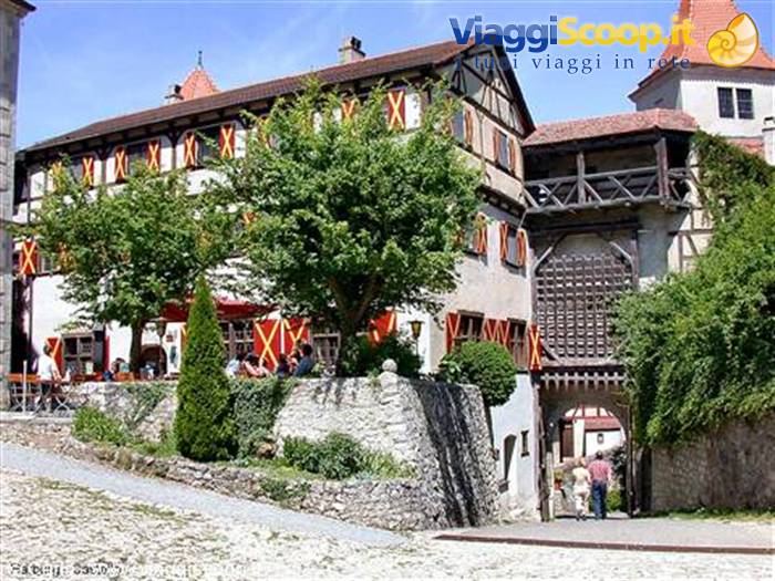 Harburg Castle: half-timbered building with red shutters, wooden gate, visitors under trees