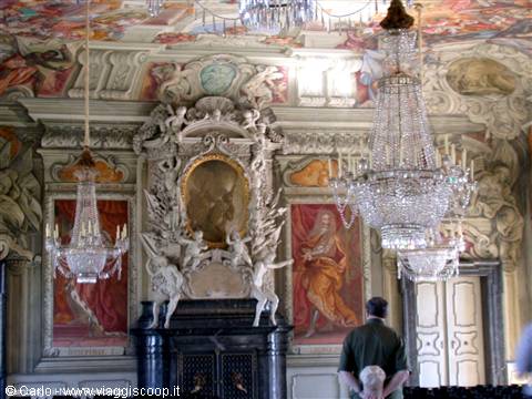 Visitor in baroque hall with frescoes, stuccoes, fireplace and crystal chandeliers