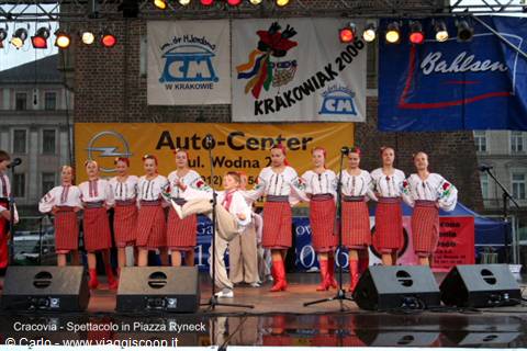 Folk dancers in traditional costumes performing on stage in Krakow's Rynek