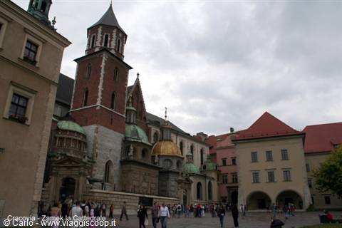 Tourists walk in front of Wawel Cathedral in Kraków, brick bell tower above
