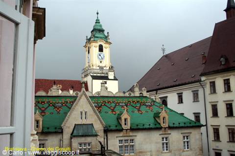 Clock tower and green tiled roofs of Bratislava's Old Town Hall under grey sky