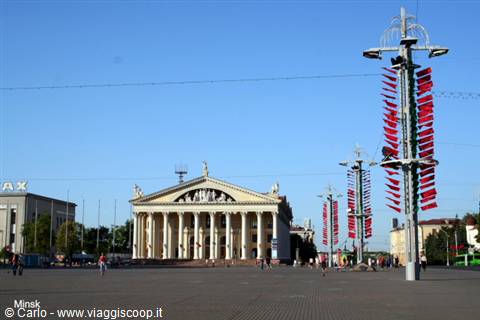 Minsk: neoclassical colonnaded building on a sunny square, red flags on lampposts