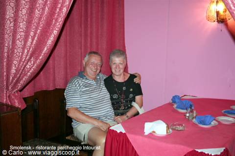 Smiling couple at a restaurant in Smolensk, red tablecloth and pink walls