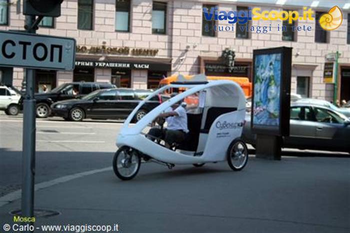 White velotaxi pedaling along the street next to a Stop sign in Moscow