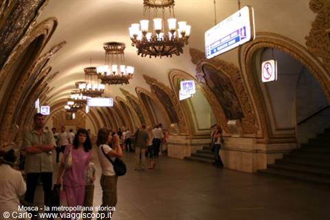 Travelers beneath golden chandeliers in Moscow's historic metro station