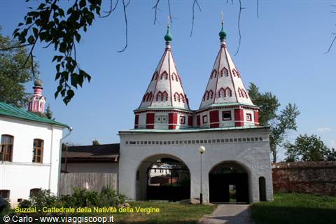 Suzdal, gateway with twin white and red tent towers under blue sky