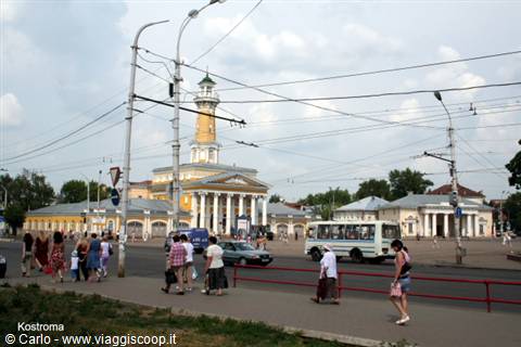 Kostroma: pedestrians and a bus pass by the yellow fire tower