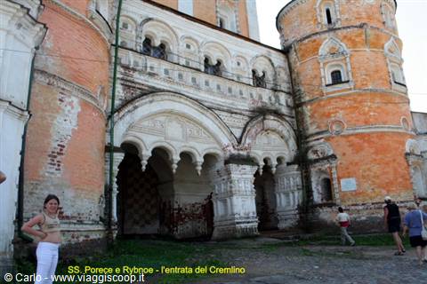 Tourists outside the Rostov Kremlin gate, weathered brick towers and carved white stone