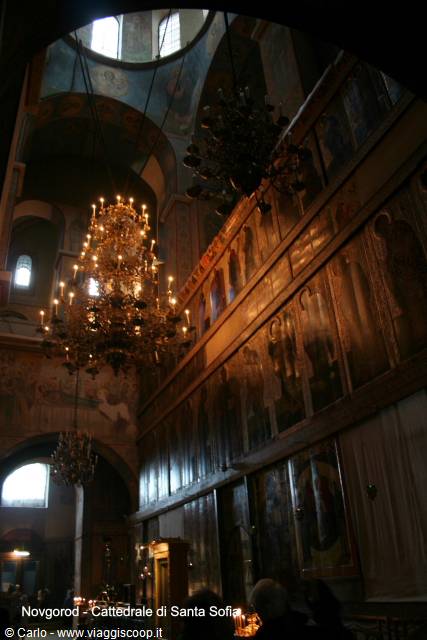 Novgorod, inside Saint Sophia Cathedral: golden iconostasis and lit chandeliers