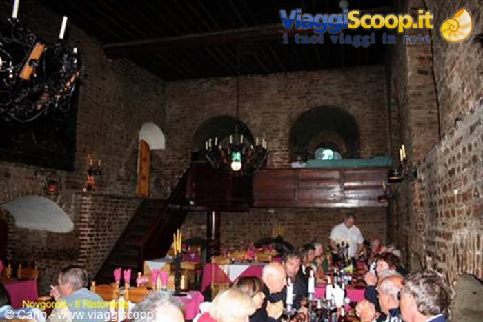 Diners eating in an old brick restaurant hall with wrought-iron chandeliers