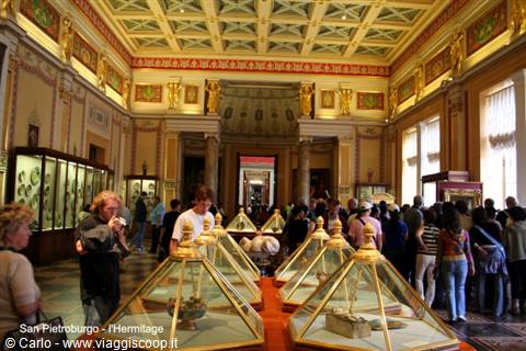 Visitors admire pyramid display cases in the gilded Hermitage hall