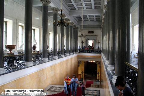 Gallery with grey columns in the Hermitage, visitors on the staircase