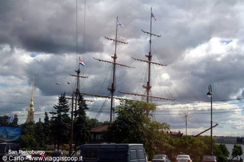 Sailing ship masts in Saint Petersburg, cloudy sky, fortress spire behind