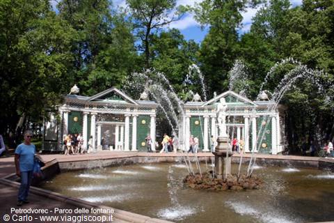 Fountain with statue at Peterhof, visitors around the basin amid painted pavilions