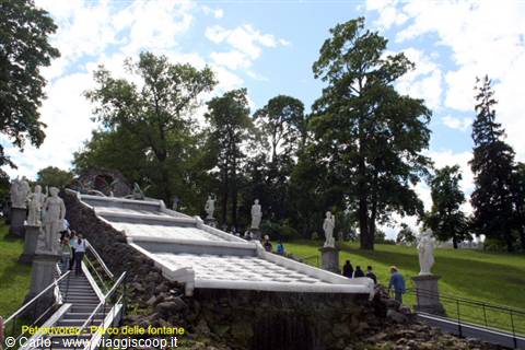 Cascade fountain staircase with marble statues at Peterhof, visitors walking nearby