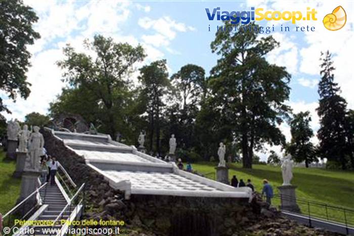 Cascade fountain staircase with marble statues at Peterhof, visitors walking nearby