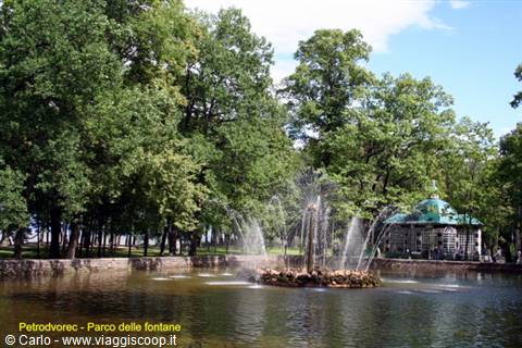 Fountain in Peterhof park pond, surrounded by trees and green pavilion