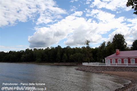 Red house with red roof on the Gulf of Finland, white clouds in the sky