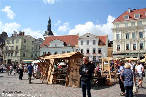 Wooden market stalls on a cobbled square, colorful houses and spire in Tallinn