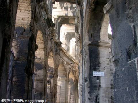 Stone arches of Arles Roman amphitheatre, light filtering through the arcades