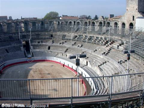 Roman amphitheater of Arles, stone tiers and sandy arena under sunny light