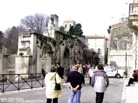 Tourists walk beside the Roman walls of the Ancient Theatre in Arles
