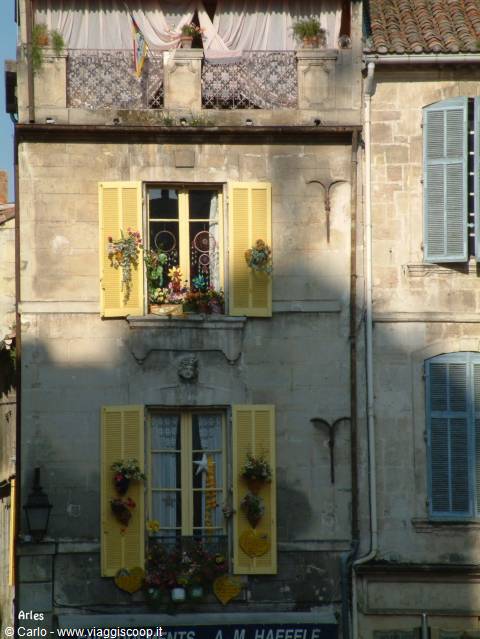 Arles: facade with yellow shutters and flowers between shadows