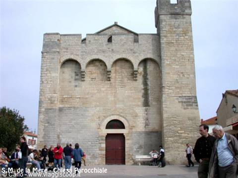 Fortified church of Saintes-Maries-de-la-Mer, pale stone, tourists on the square
