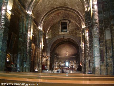 Romanesque stone church interior, barrel vaults and lit altar