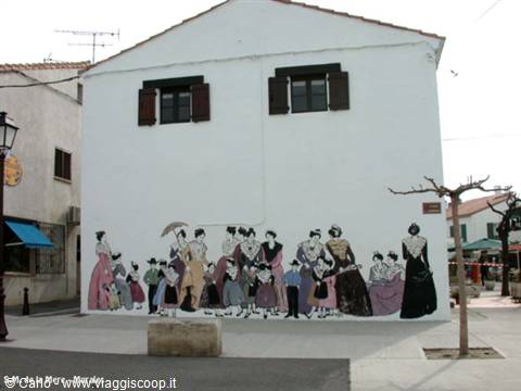 Mural of women in vintage dresses on white facade at Saintes-Maries-de-la-Mer