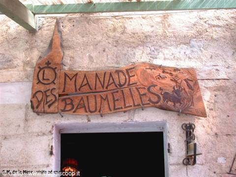 Wooden painted sign Manade des Baumelles on stone wall, Camargue