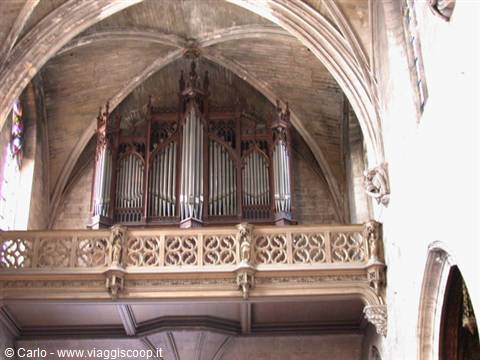 Large wooden organ beneath Gothic vaults inside a church in Provence