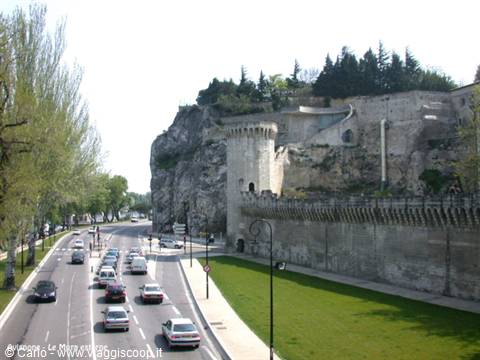 Medieval tower and Avignon walls above a busy road, daytime light