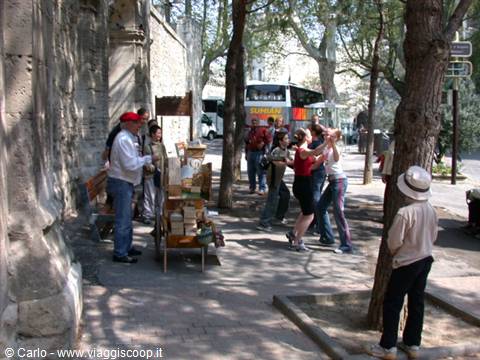 Tourists dancing in the shade of trees near a stone church in Les Saintes-Maries-de-la-Mer