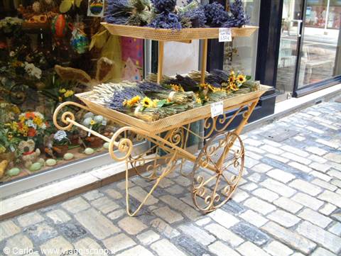 Wrought iron cart with lavender bundles and sunflowers on cobblestones
