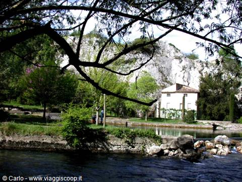White house among limestone cliffs by the river at Fontaine-de-Vaucluse