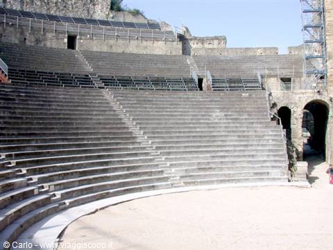 Roman amphitheatre of Arles, stone tiers and arches in sunlight