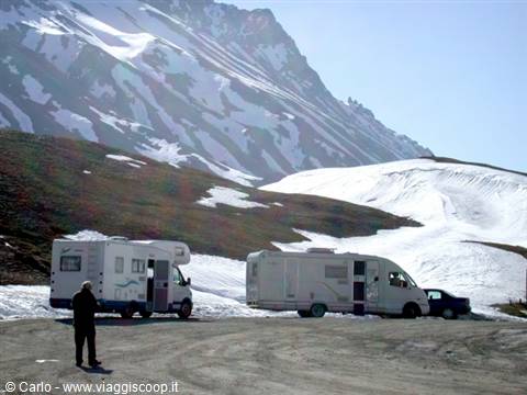 Campervans and car parked on snowy high mountain road, man walking