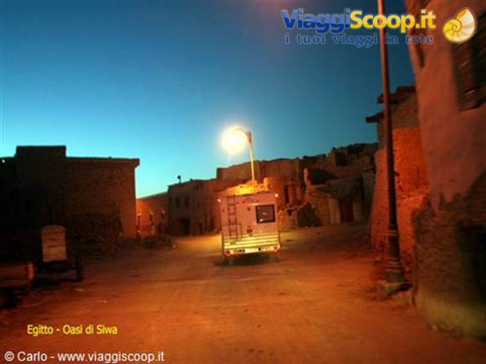 Camper van parked at night among mud-brick houses in Siwa Oasis