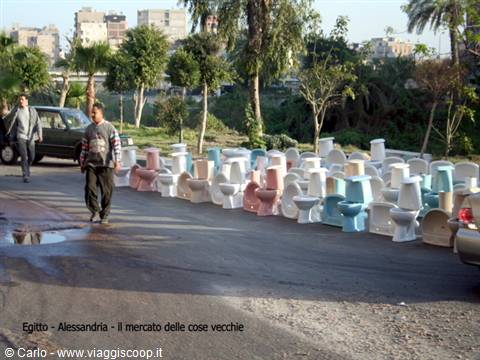 Men walk past rows of used toilets lined along the street