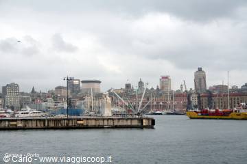 Genoa old harbor: pier, ships and towers under cloudy sky